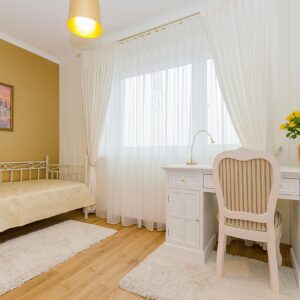 Elegant minimalist bedroom with white furniture and warm decor accents.